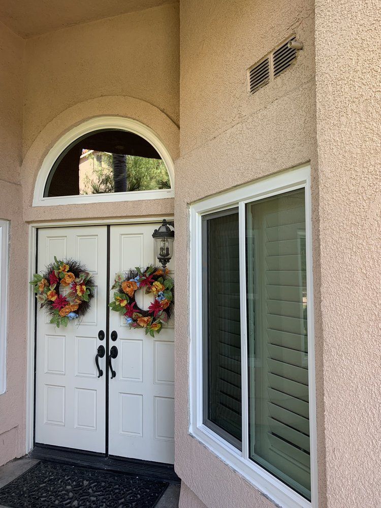 The front door of a house with two wreaths on it.
