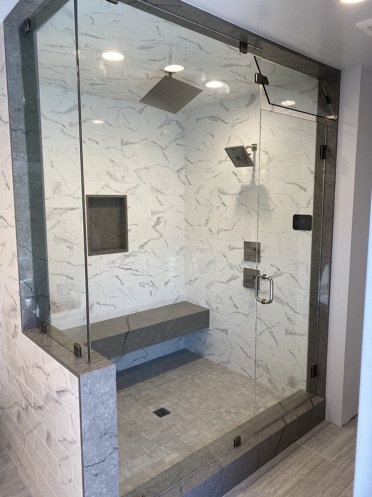 A bathroom with a glass shower door and a bench.