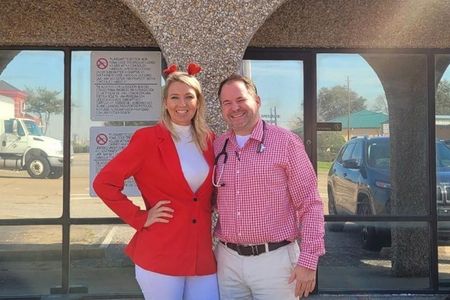 A man and a woman are posing for a picture in front of a building