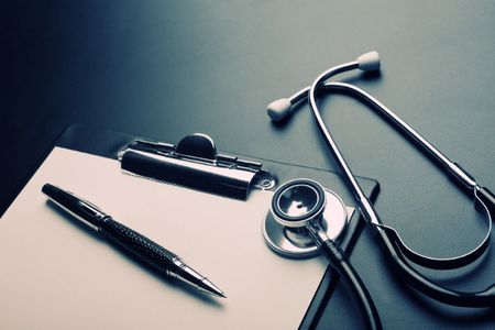 A clipboard with a pen and stethoscope on it