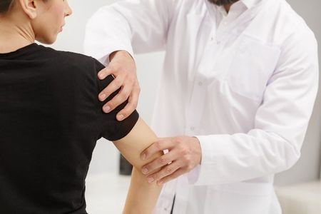 A doctor is examining a patient 's arm and shoulder.