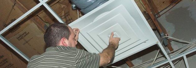 Man reaching up to open filter holder for air conditioning filter in ceiling