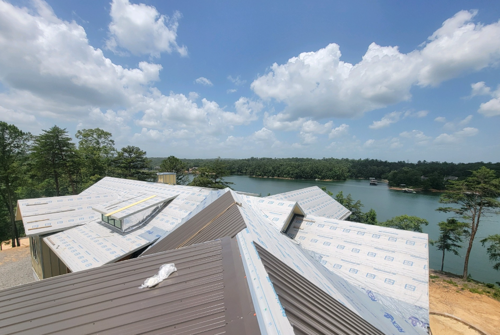 An aerial view of a house under construction with a lake in the background.
