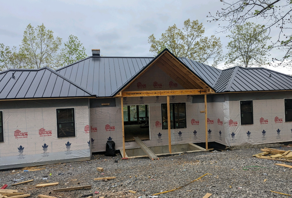 A large house is being built with a metal roof.