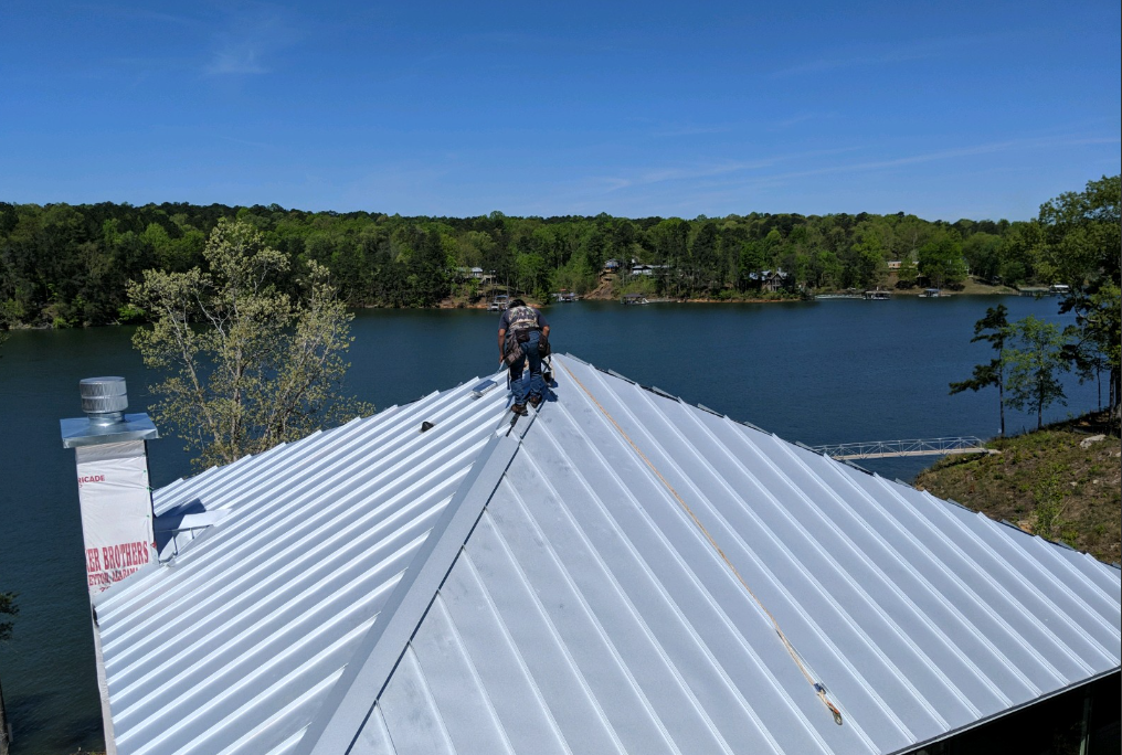 A man is standing on the roof of a house overlooking a lake.