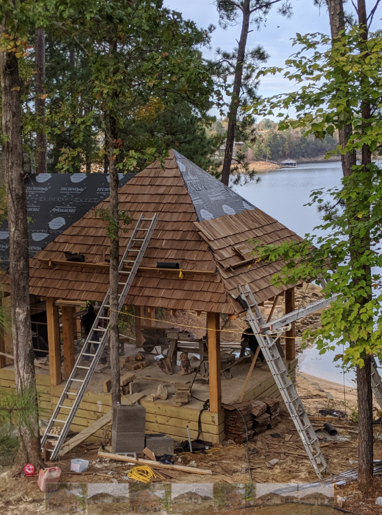 A wooden gazebo is being built on the shore of a lake.