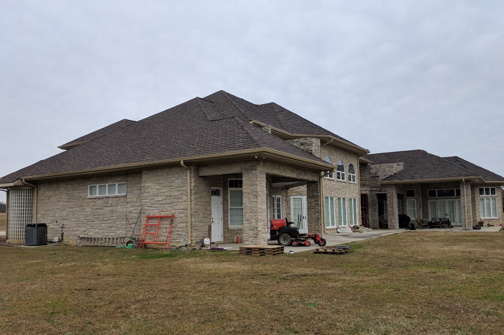 A large brick house is sitting in the middle of a grassy field.