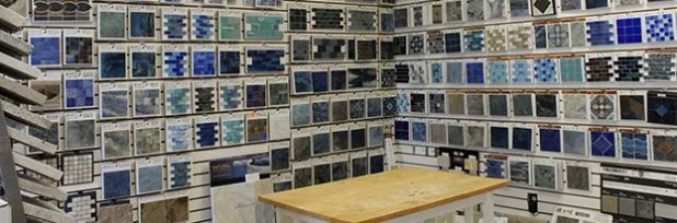 Wall of blue and white tile samples surrounding a small wooden table in a showroom