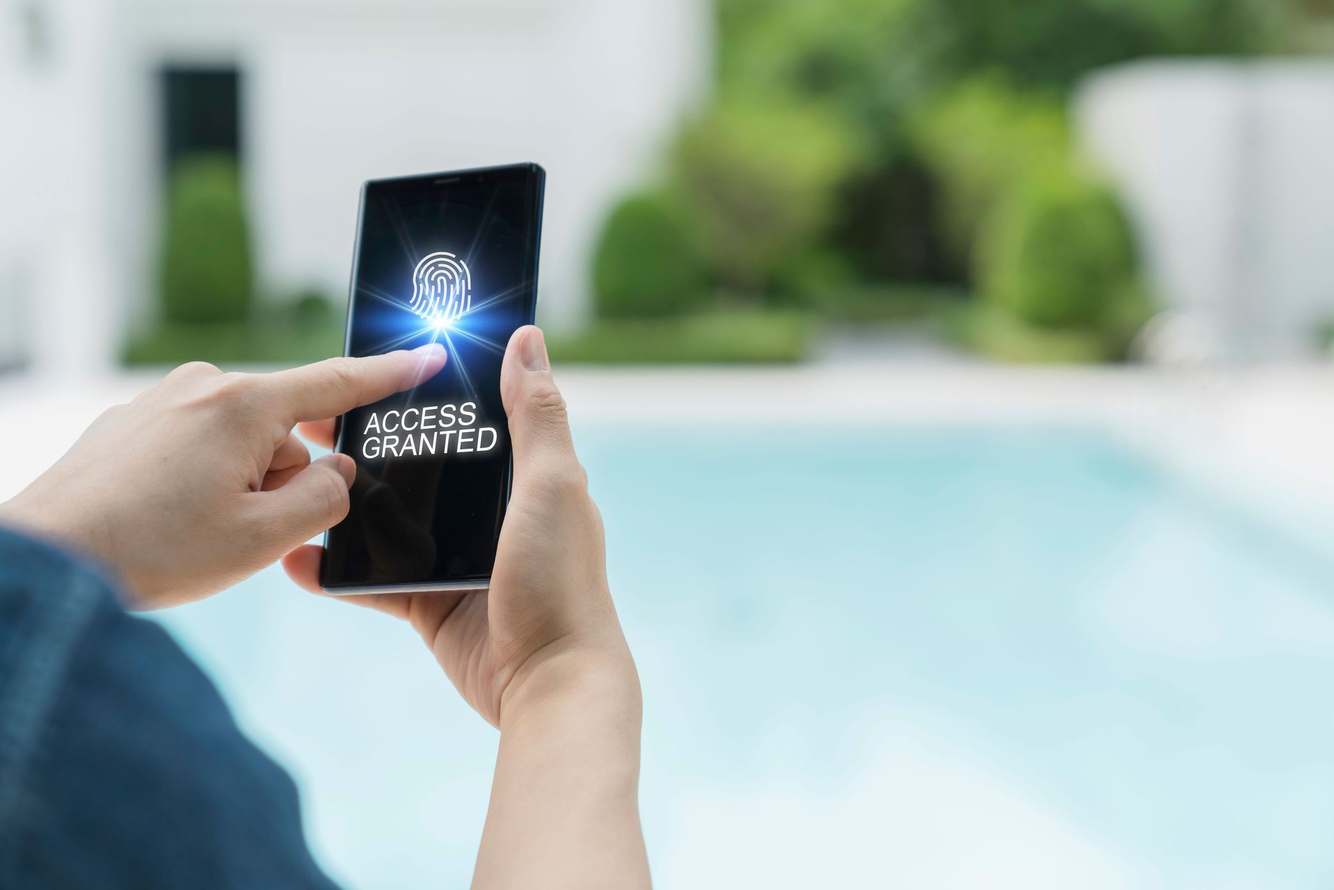 Hands holding a smartphone with a glowing app icon by a swimming pool