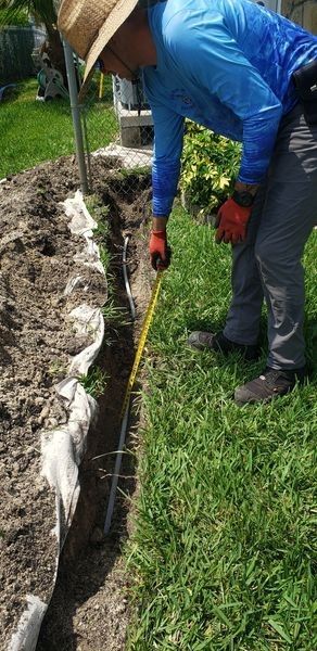 A man is measuring a hole in the ground with a tape measure.
