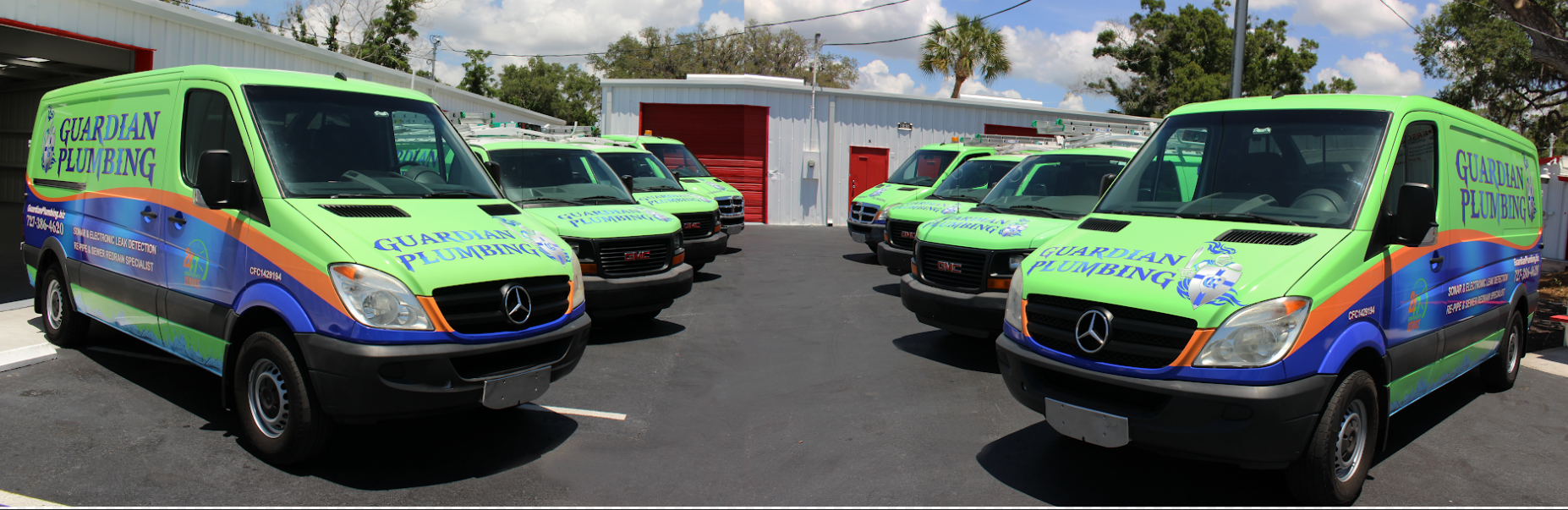 A row of green and blue vans are parked in a parking lot.