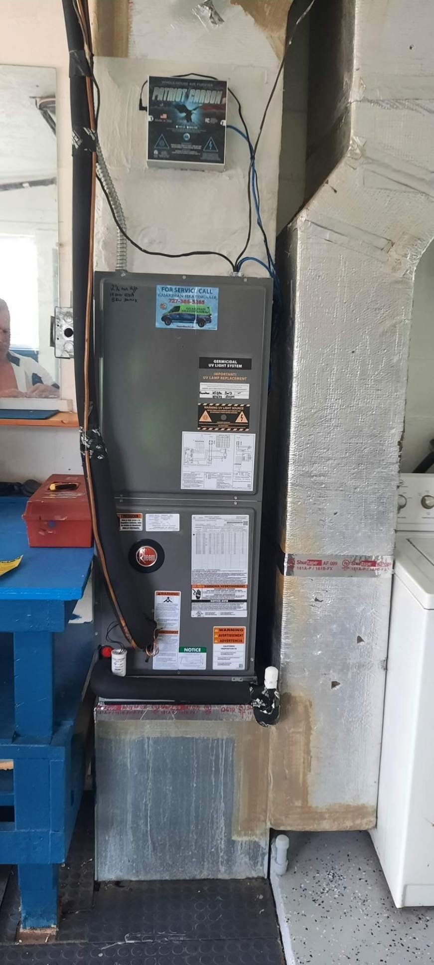 An air conditioner is sitting in a room next to a washer and dryer.