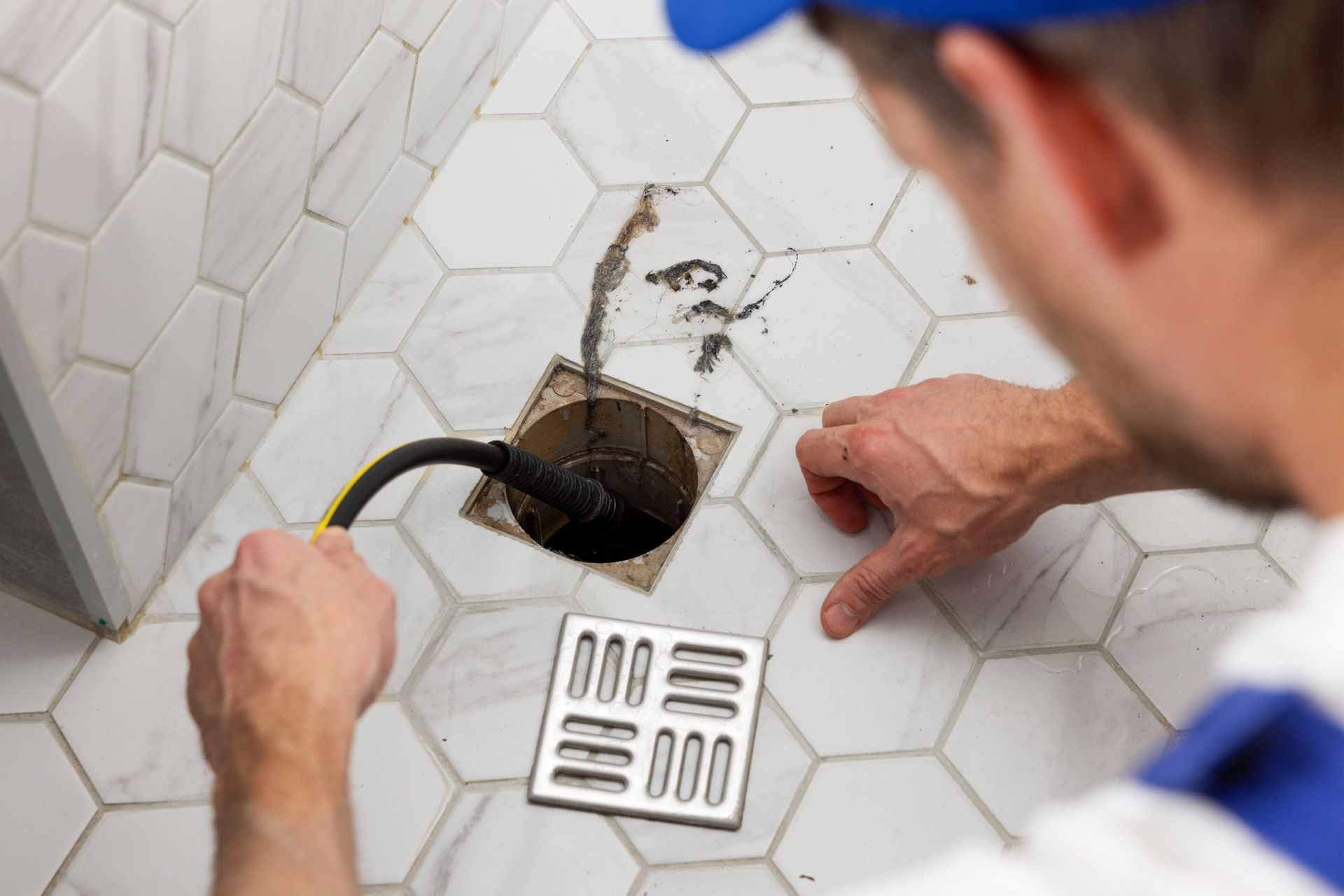 man using drain cleaning on a shower drain