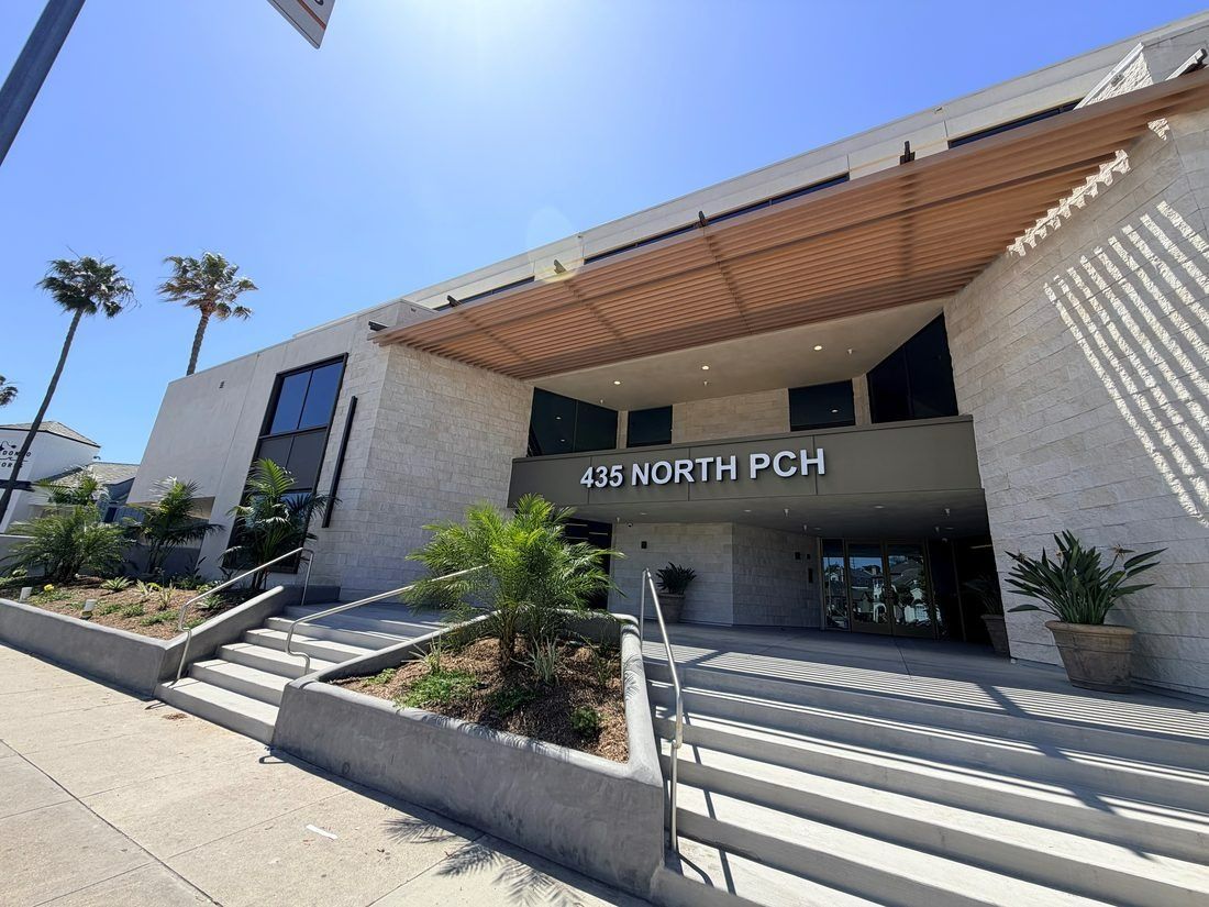 Modern building entrance with steps, palm trees, and sign reading “135 NORTH PCH”