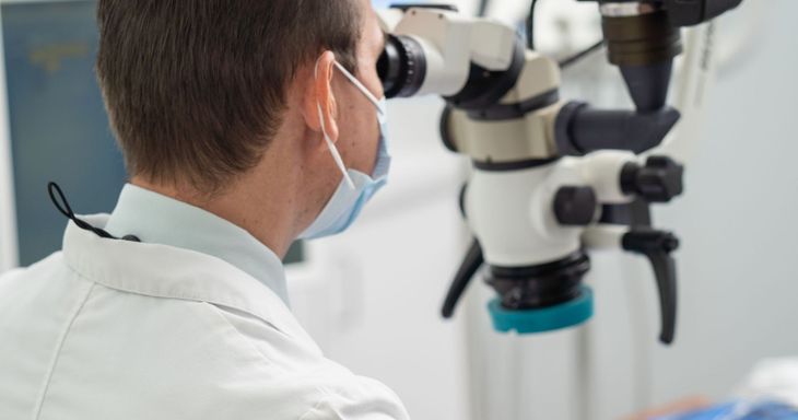 A dentist is looking through a microscope in a dental office.