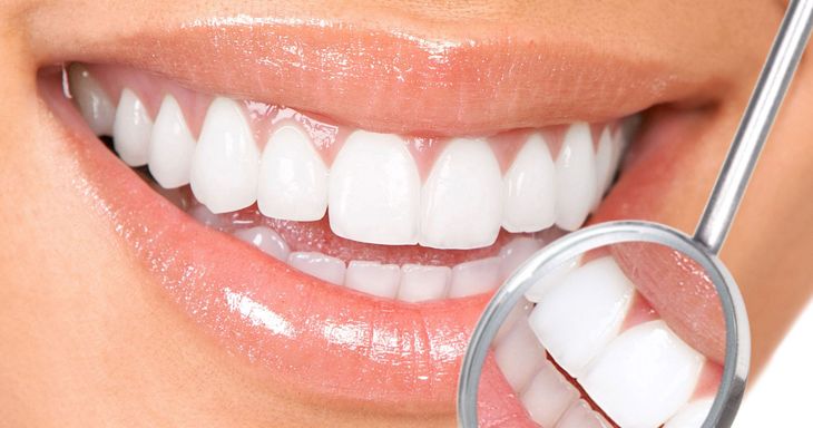 A man is sitting in a dental chair getting his teeth examined by a dentist.