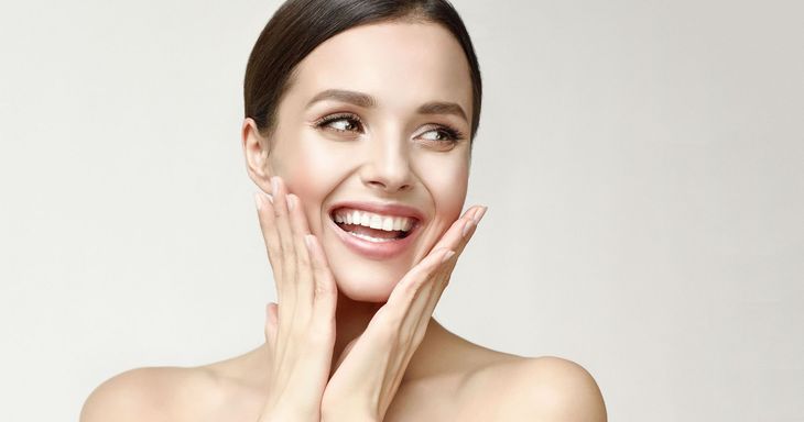 A woman is pointing at her gums with her finger.