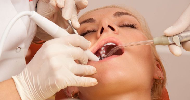 A woman is getting her teeth examined by a dentist.