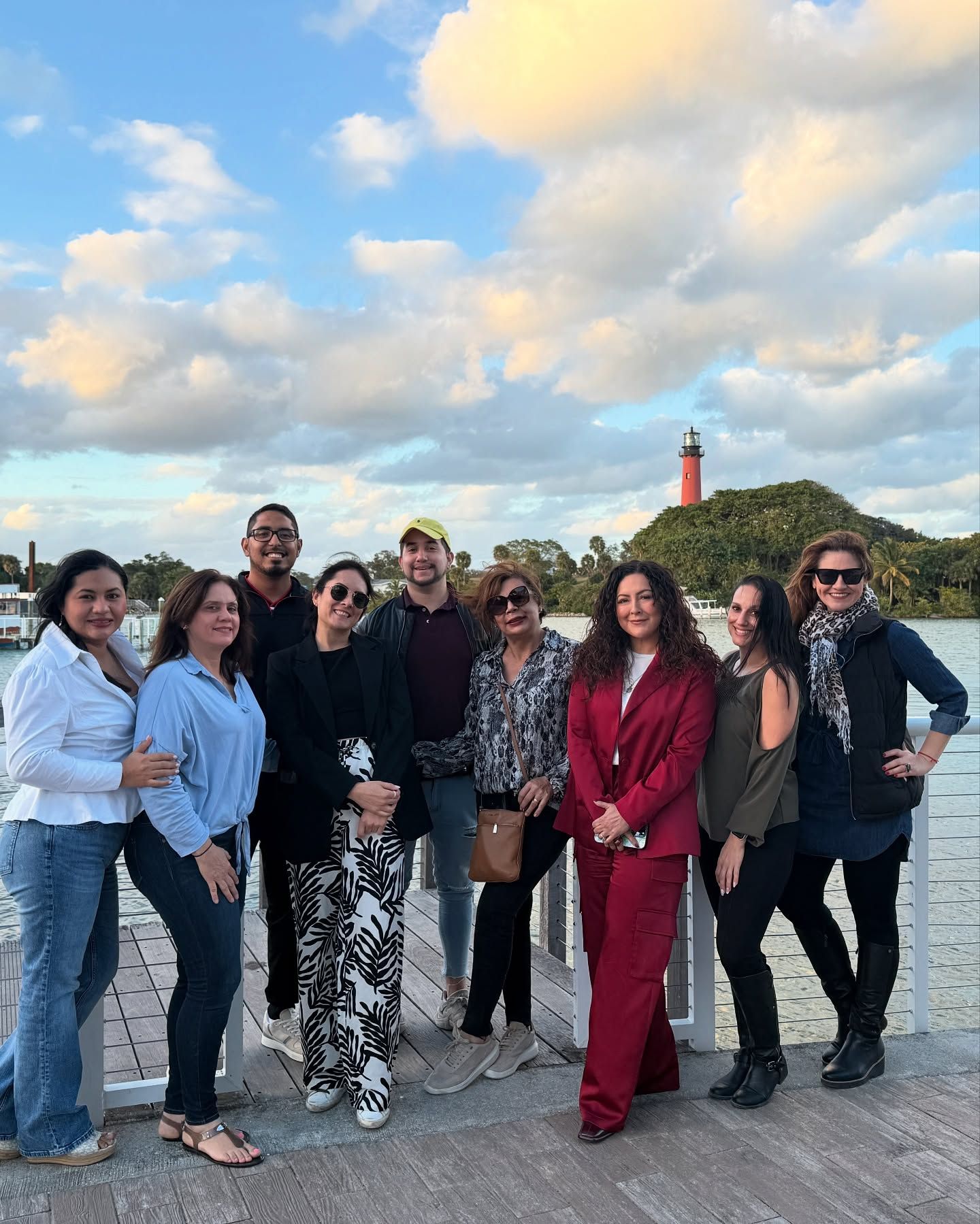 A group of people are posing for a picture in front of a lighthouse.