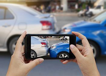 Hands using smartphone to take photo of car accident site