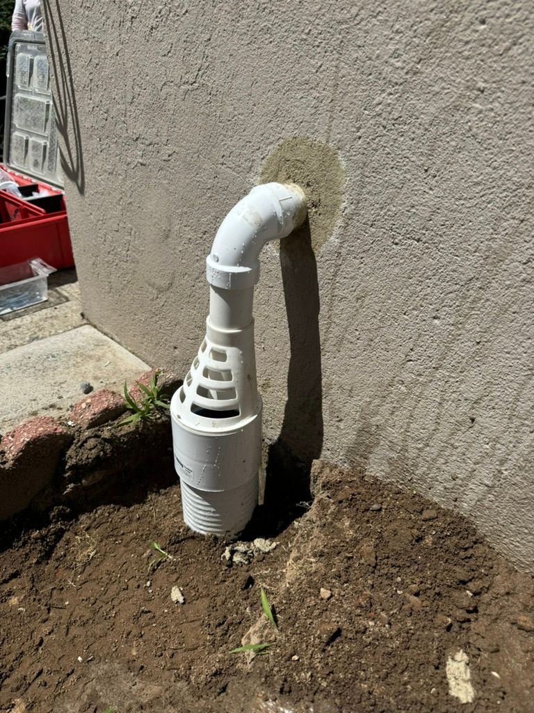 Outside of house with white pipe going inside and in ground