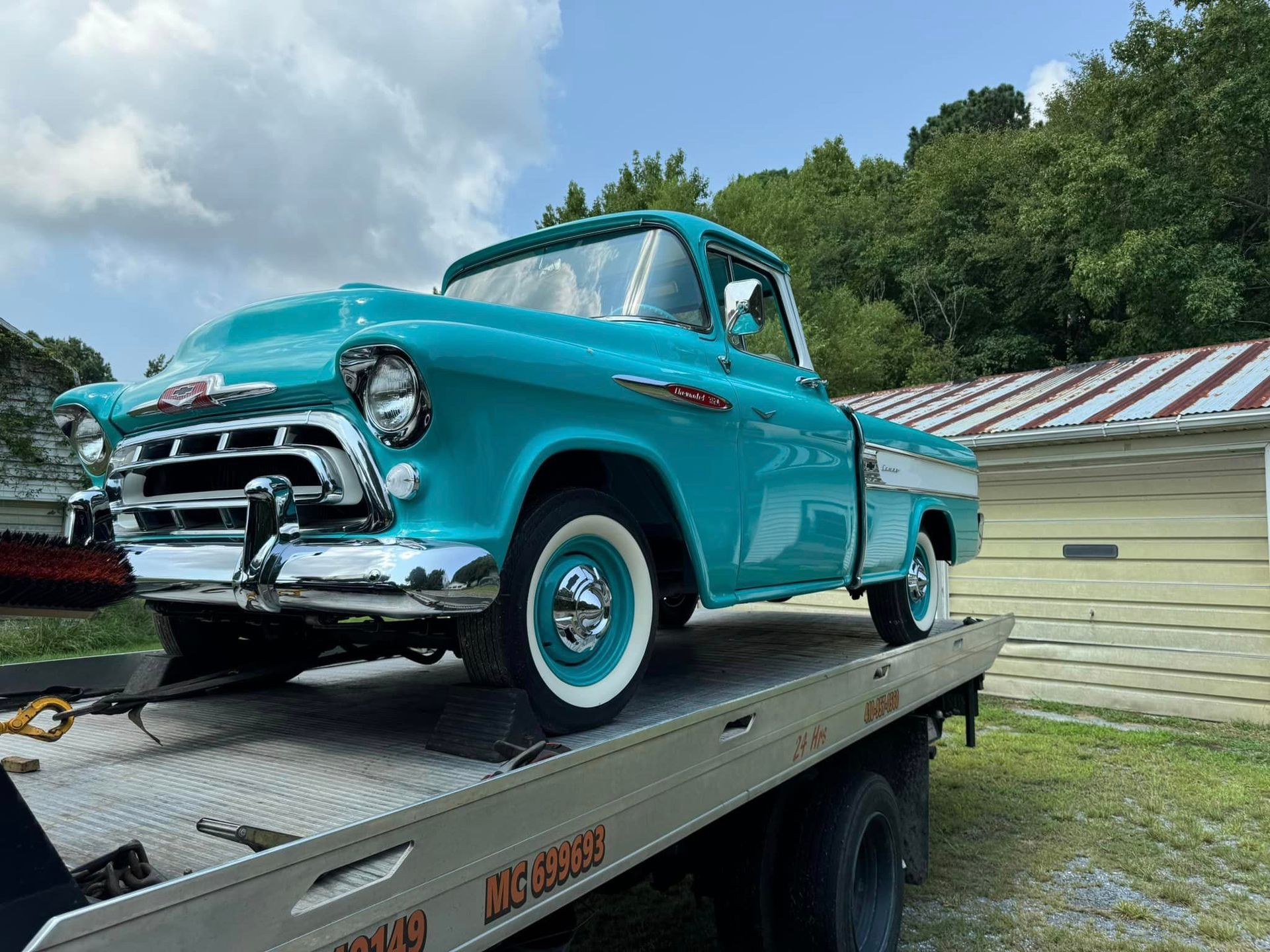 A blue truck is sitting on top of a tow truck.