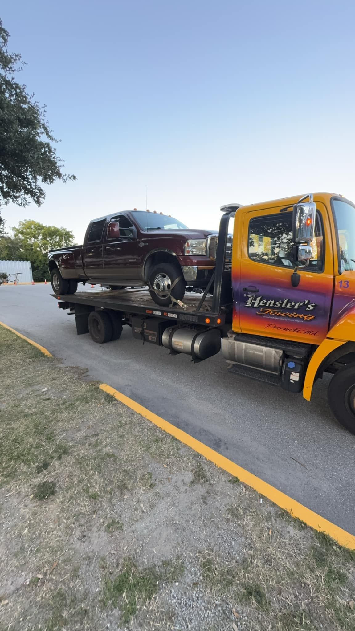 A tow truck is carrying a truck on the back of it.