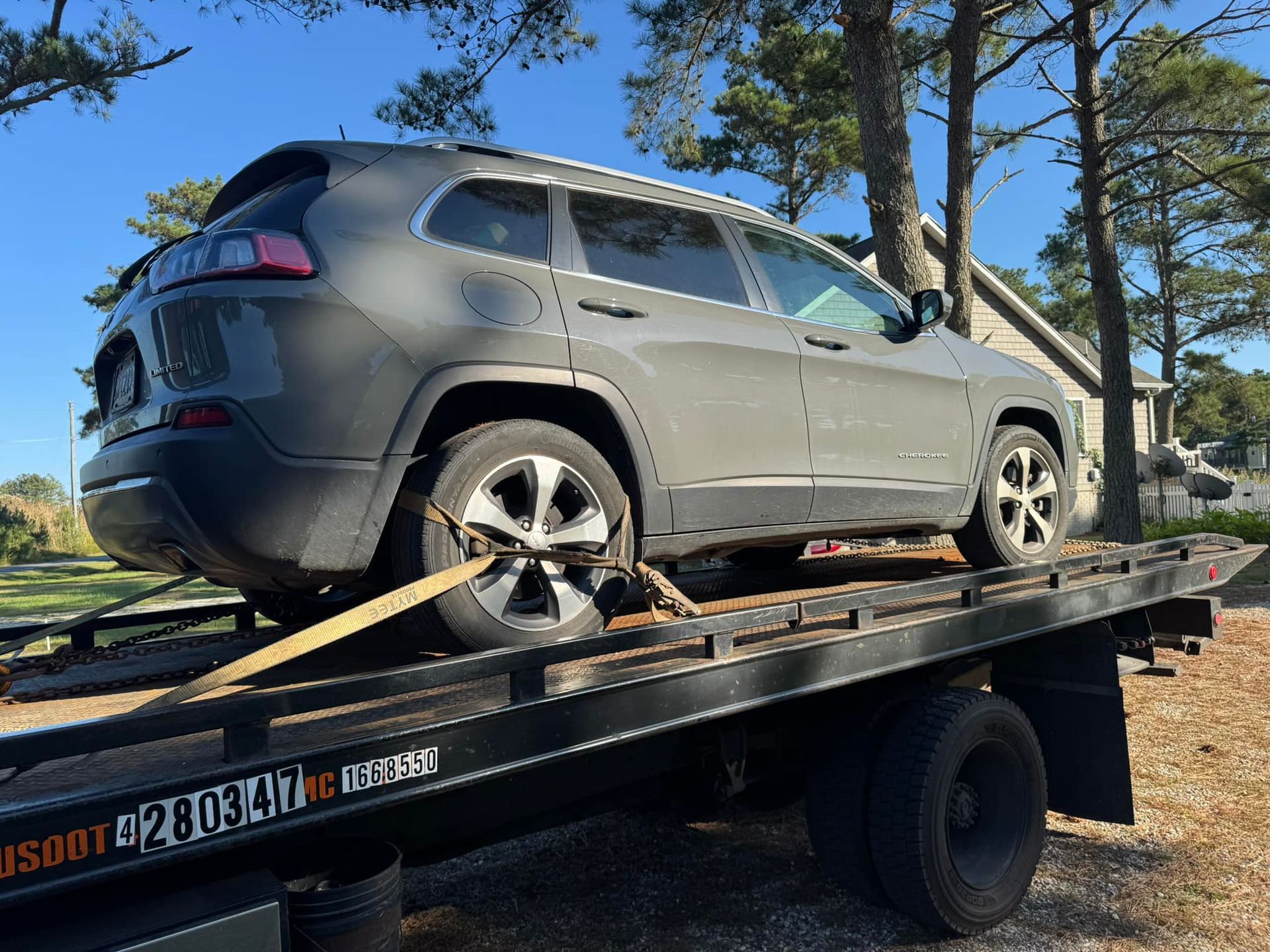 A jeep is sitting on top of a tow truck.