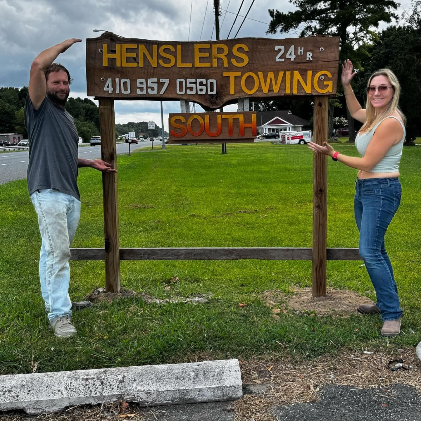 A man and a woman standing in front of a henslers towing sign