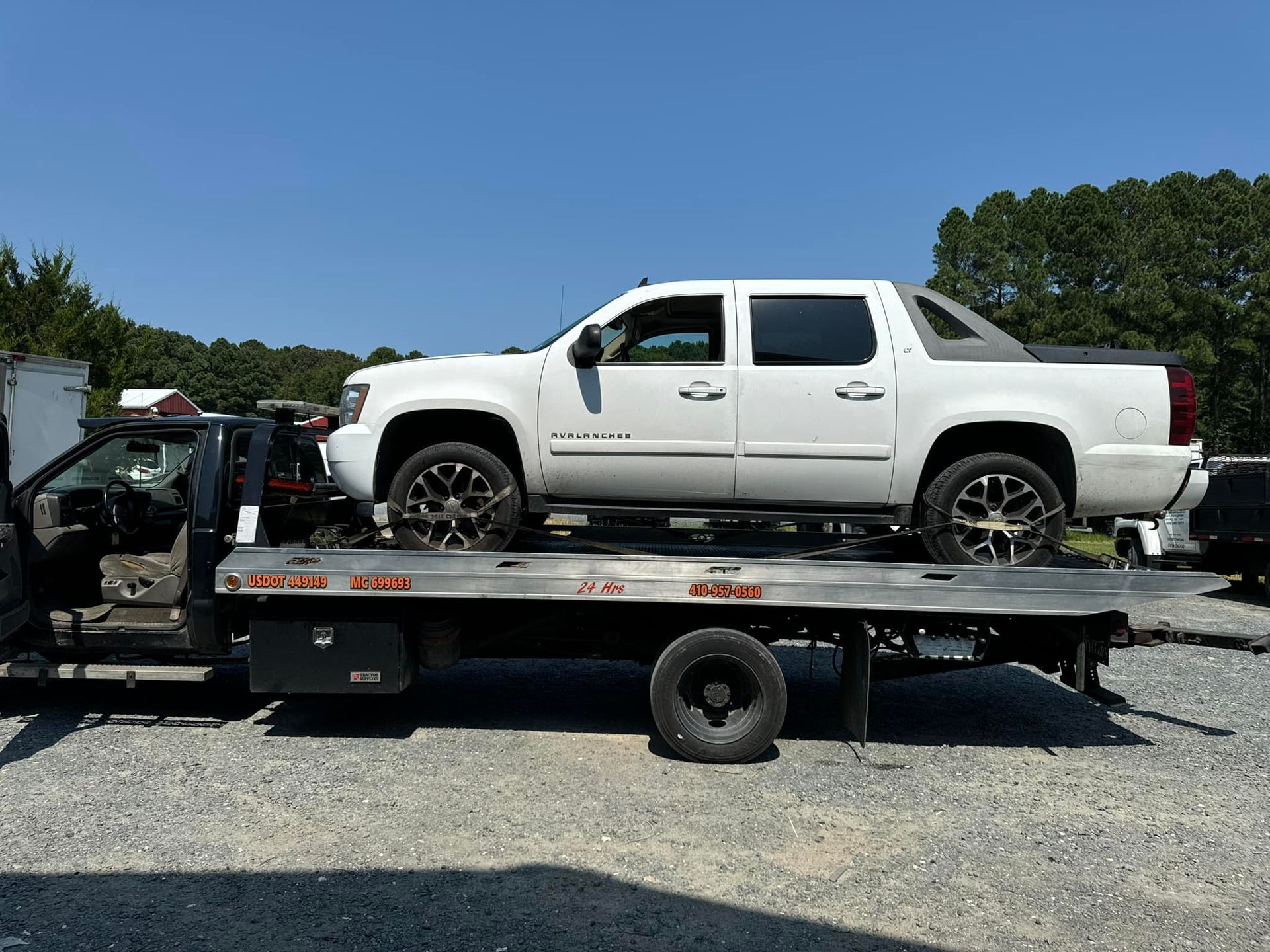 A white truck is sitting on top of a tow truck.