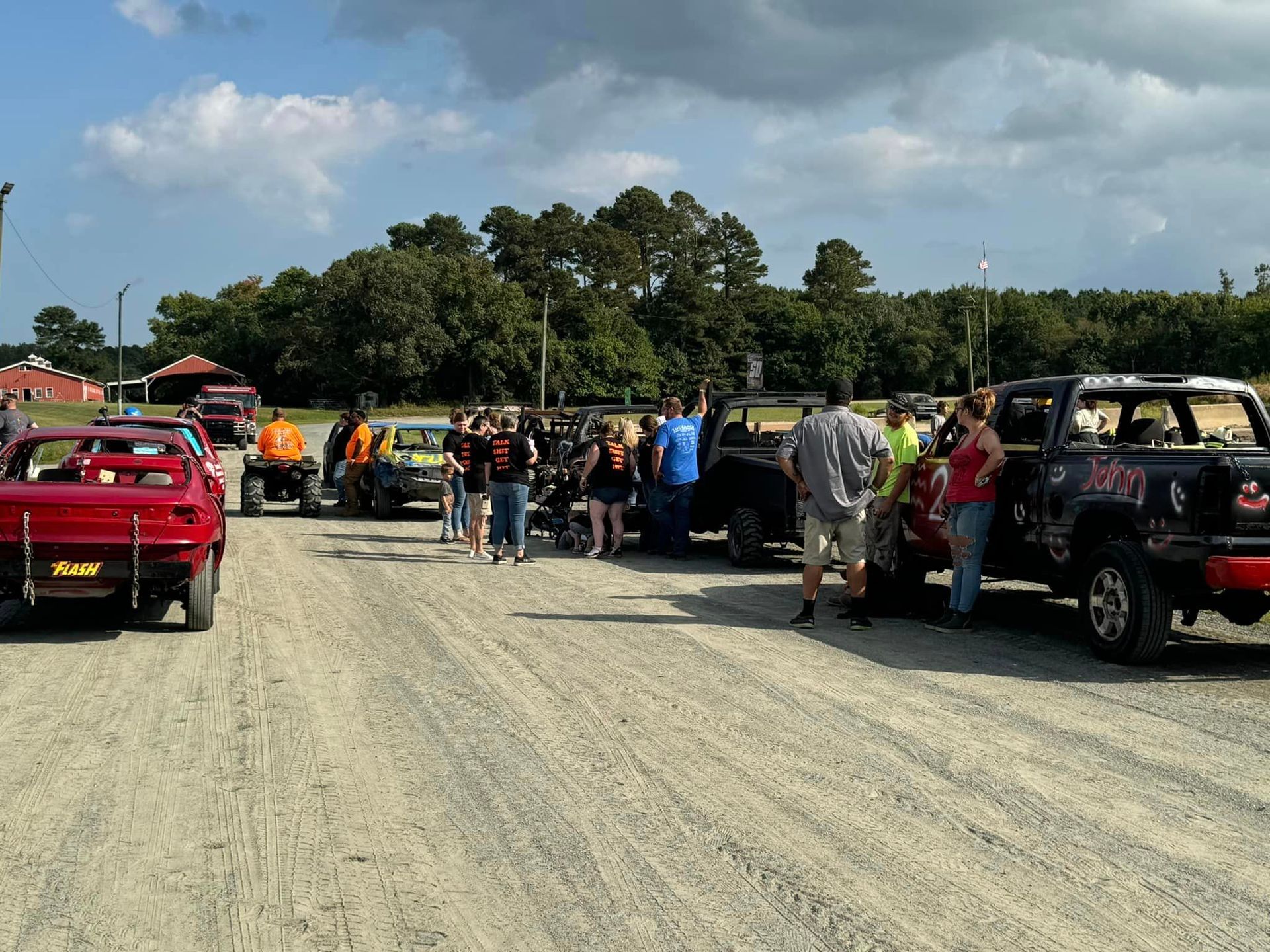 A group of people are standing in front of a row of pickup trucks.