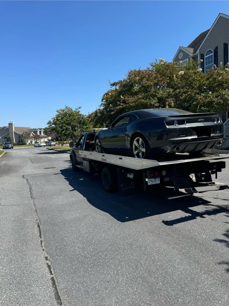 A black car is sitting on top of a tow truck.