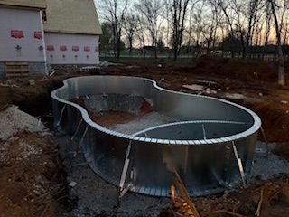 A metal frame for an in-ground swimming pool under construction in a residential yard. 
