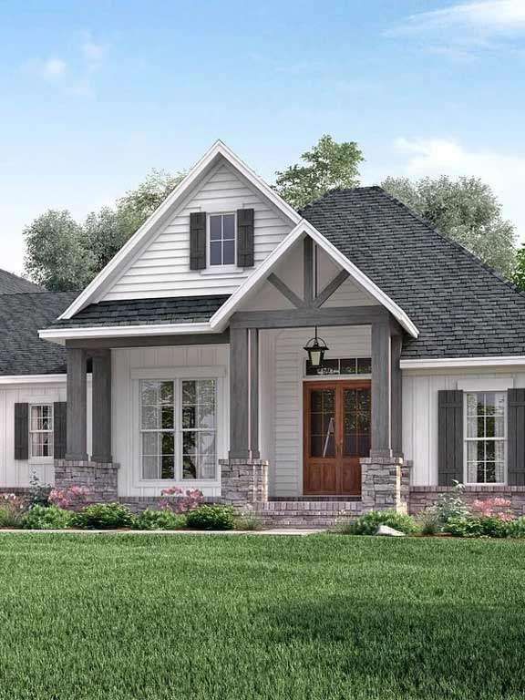 A white house with a black roof and shutters is sitting on top of a lush green lawn.