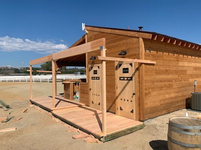 Wooden building with a porch under construction, against a blue sky, outdoor setting.