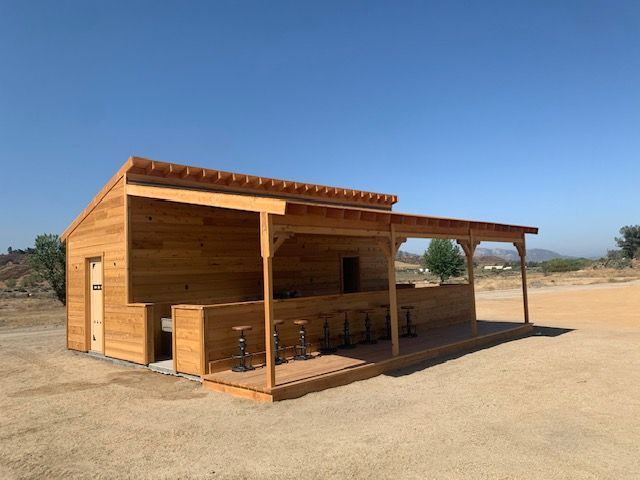 Wooden bar structure with seating under a covered patio on a sunny day.