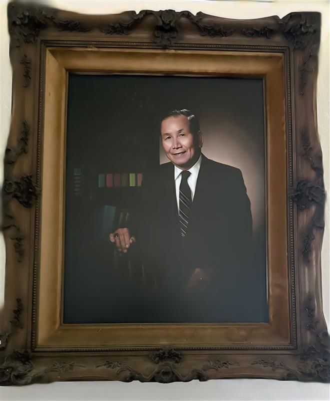Formal portrait of an older Asian man in a suit, smiling, framed in ornate gold.