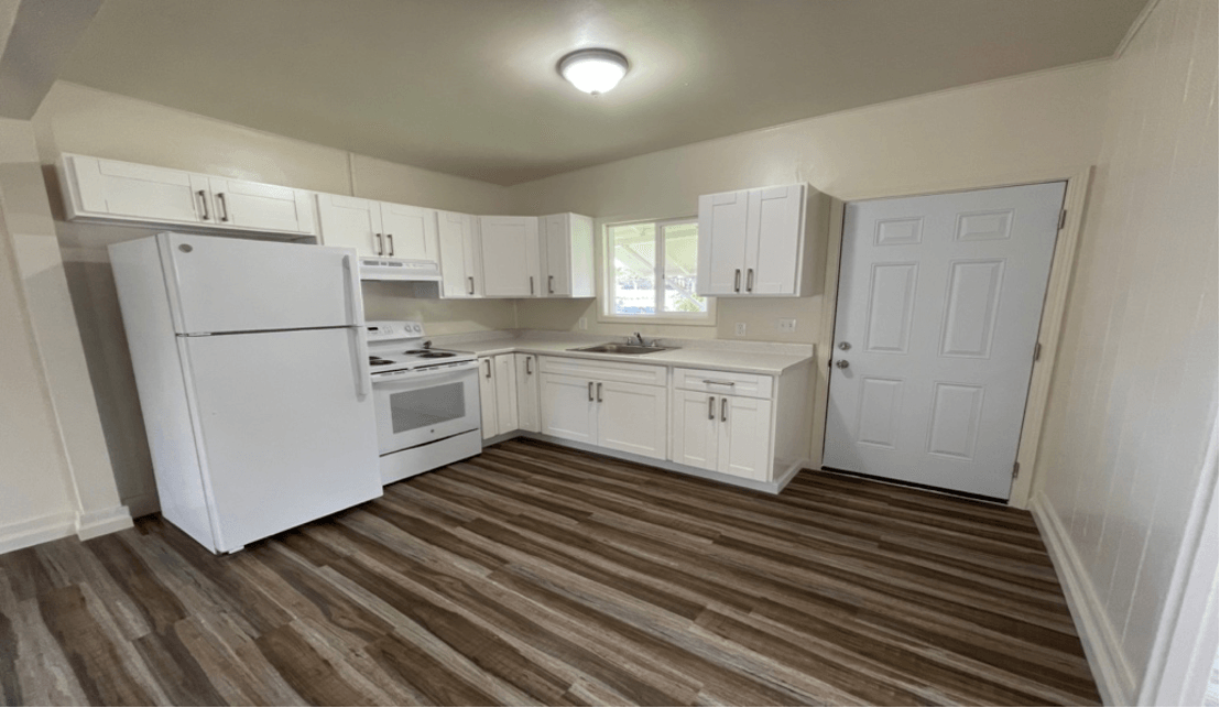 White kitchen with cabinets, appliances, and a wooden floor.