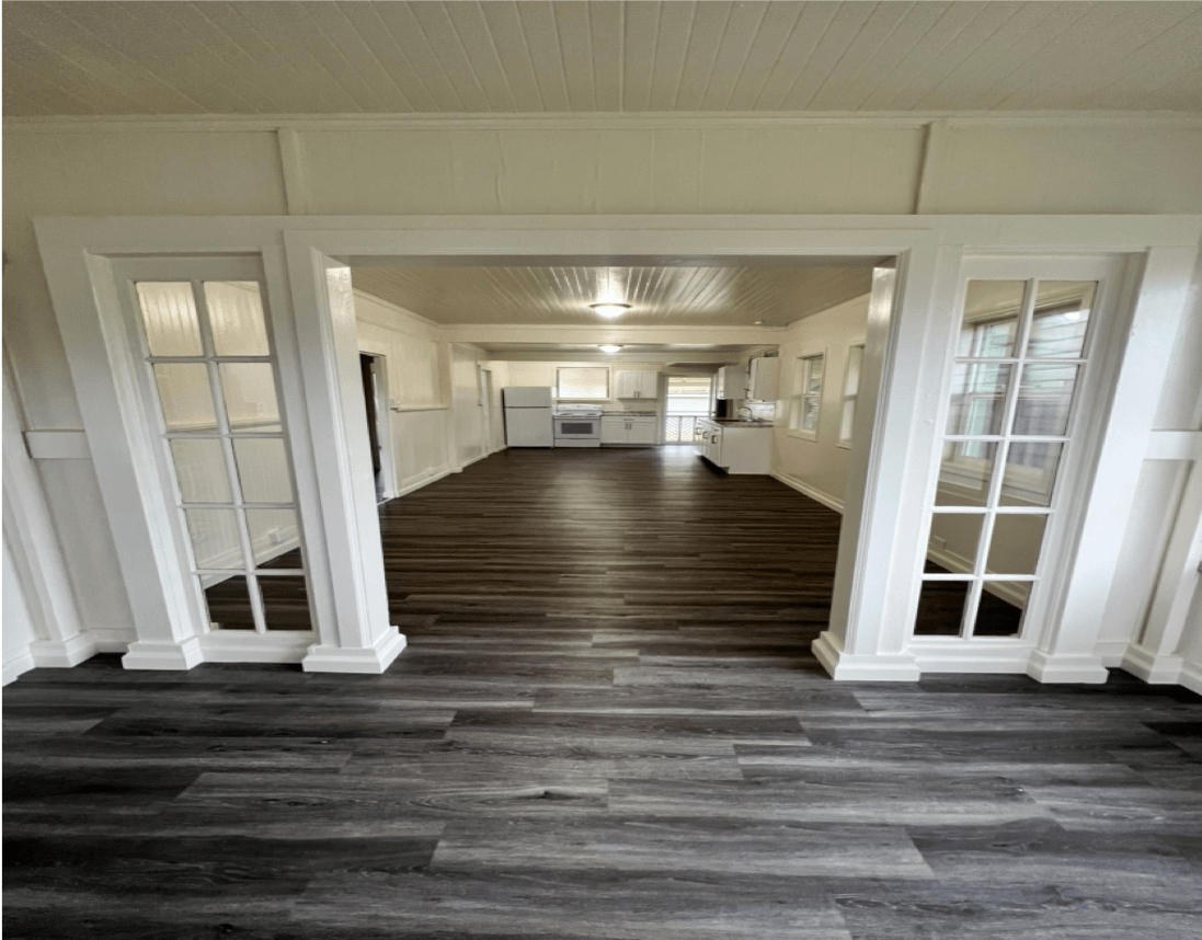 Interior of a renovated home with wood flooring and an open floor plan, white trim and french doors.