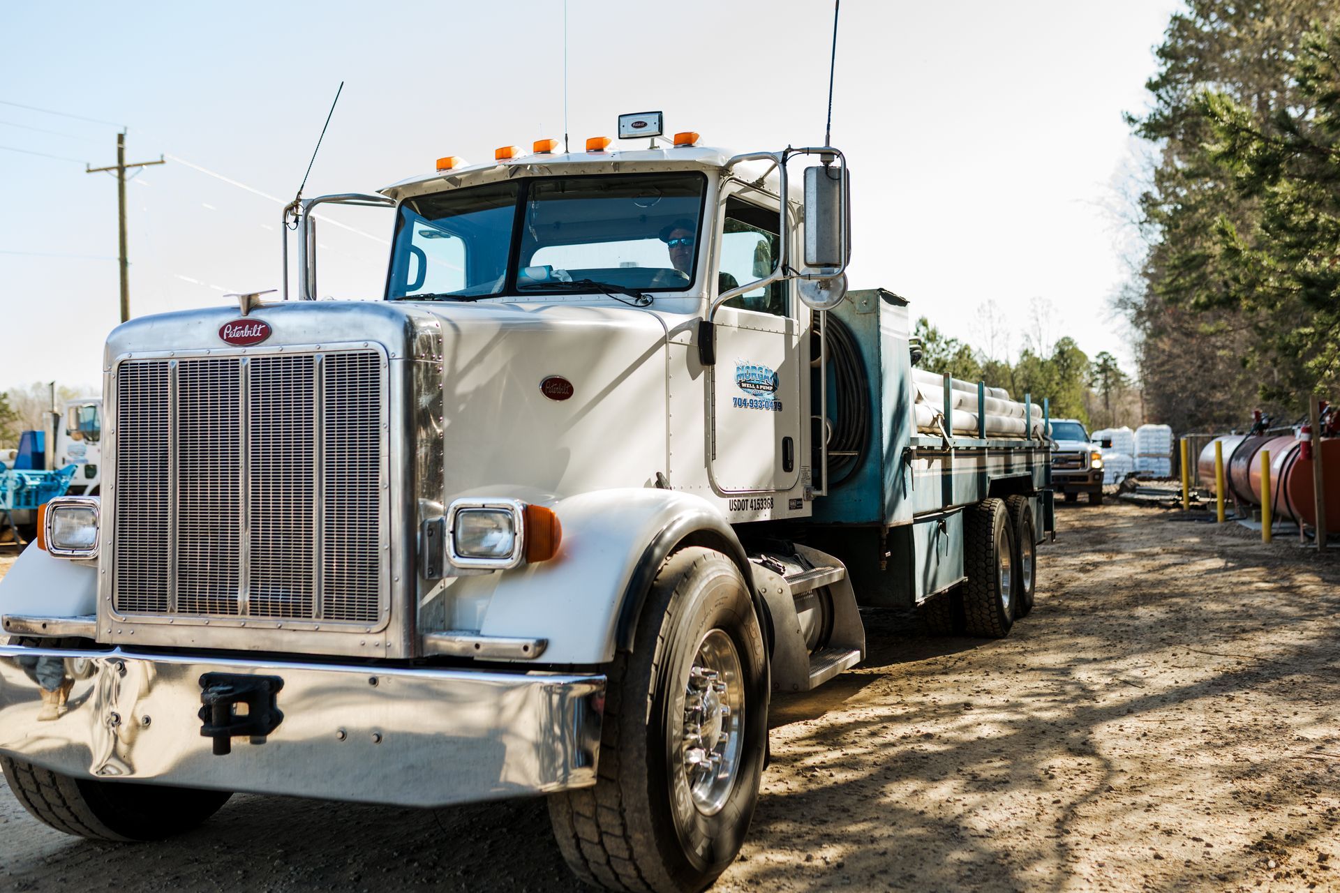 A white peterbilt semi truck is parked on a dirt road