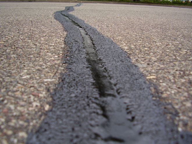 Cracked asphalt road with a long dark seam running through the center