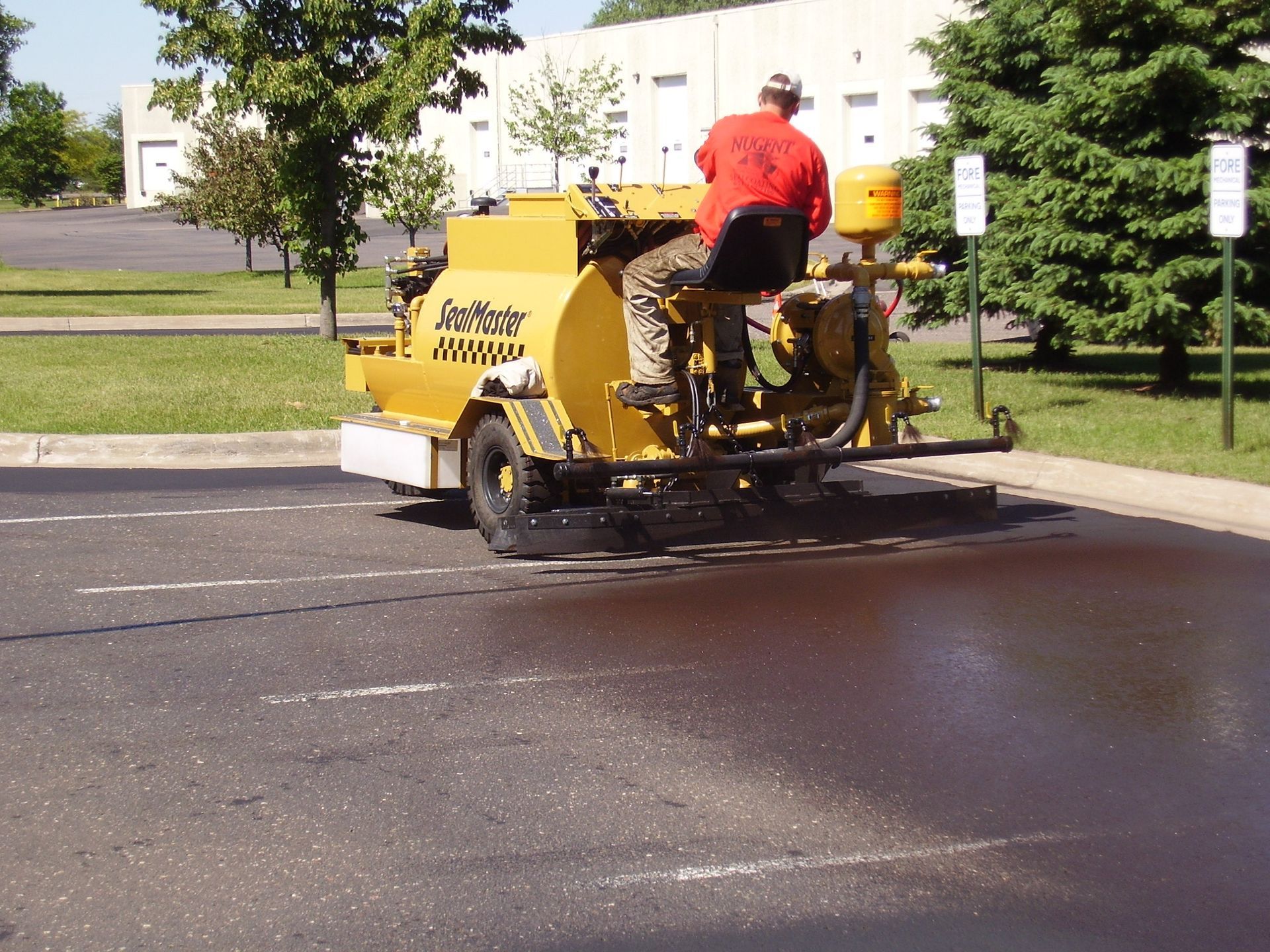 Worker operating a yellow asphalt paving machine on a road surface outdoors