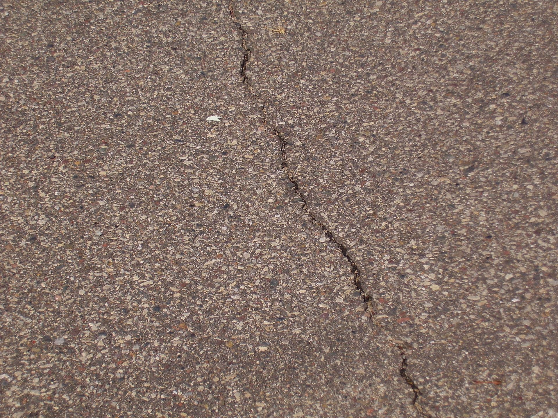 Close-up of cracked asphalt pavement with a diagonal split.