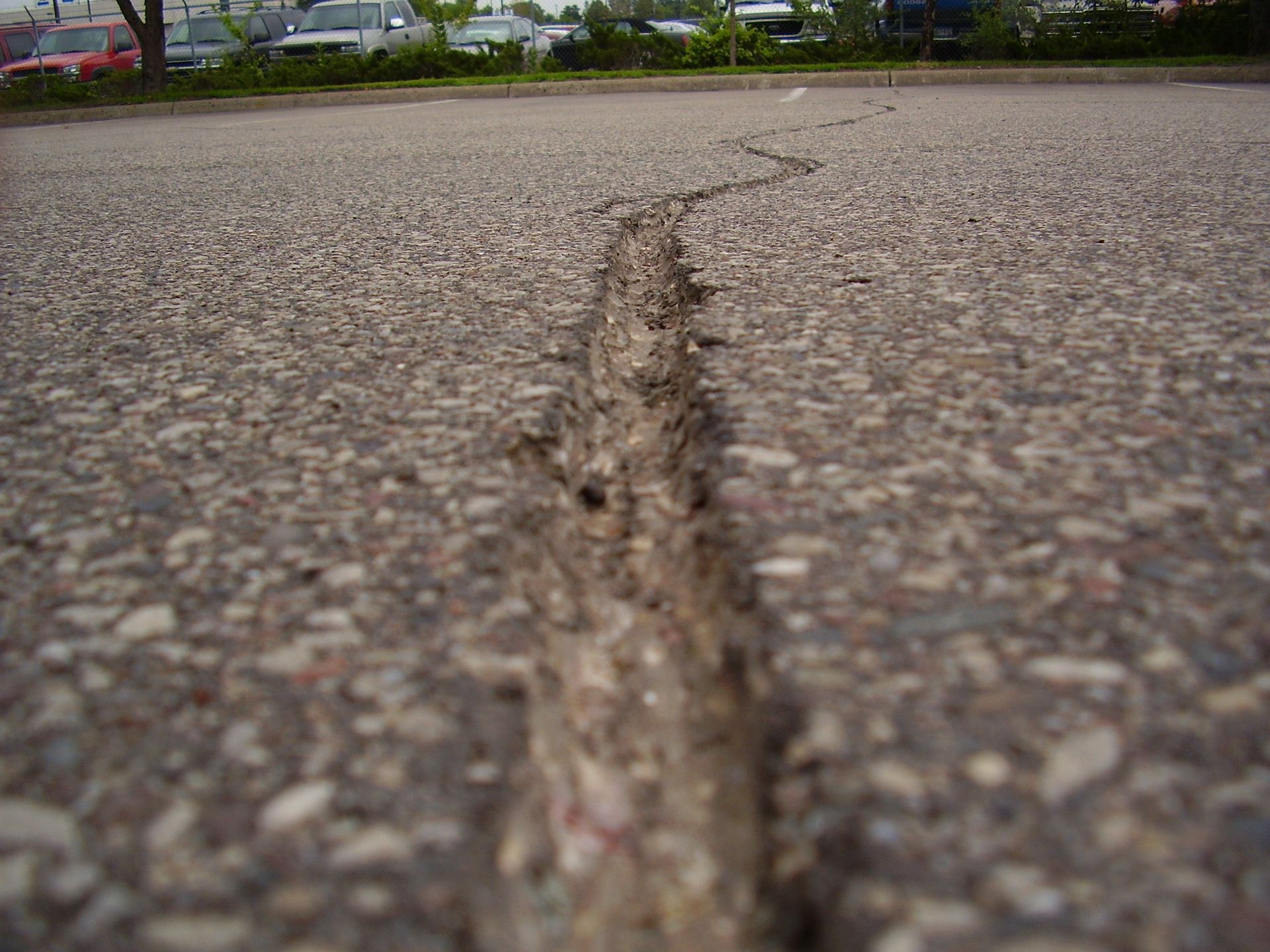 Close-up of a cracked asphalt road with a deep seam running through it