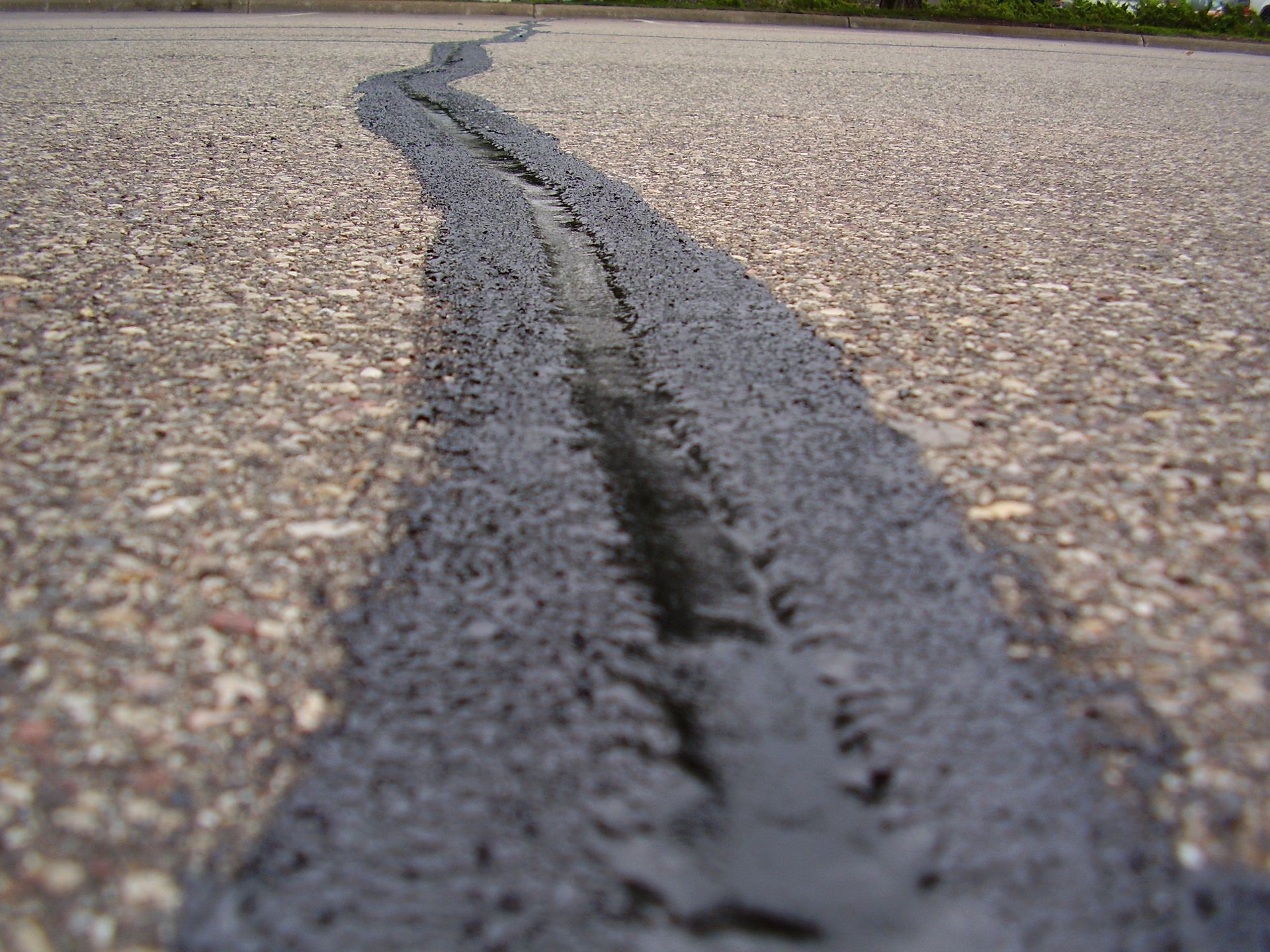 Cracked asphalt road with a long dark crack running through the center