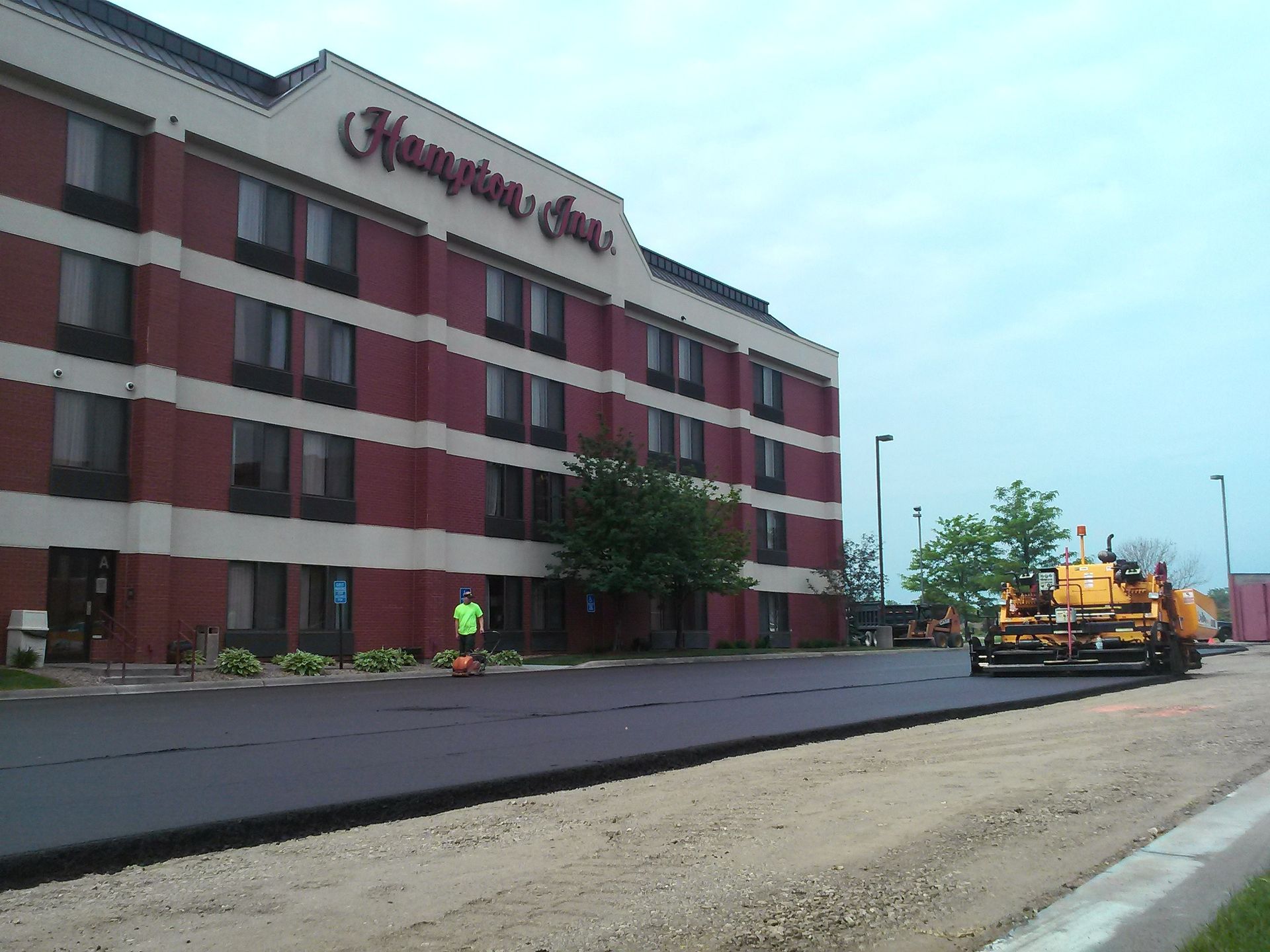 A red-and-white hotel building beside a road, with construction equipment on the right.