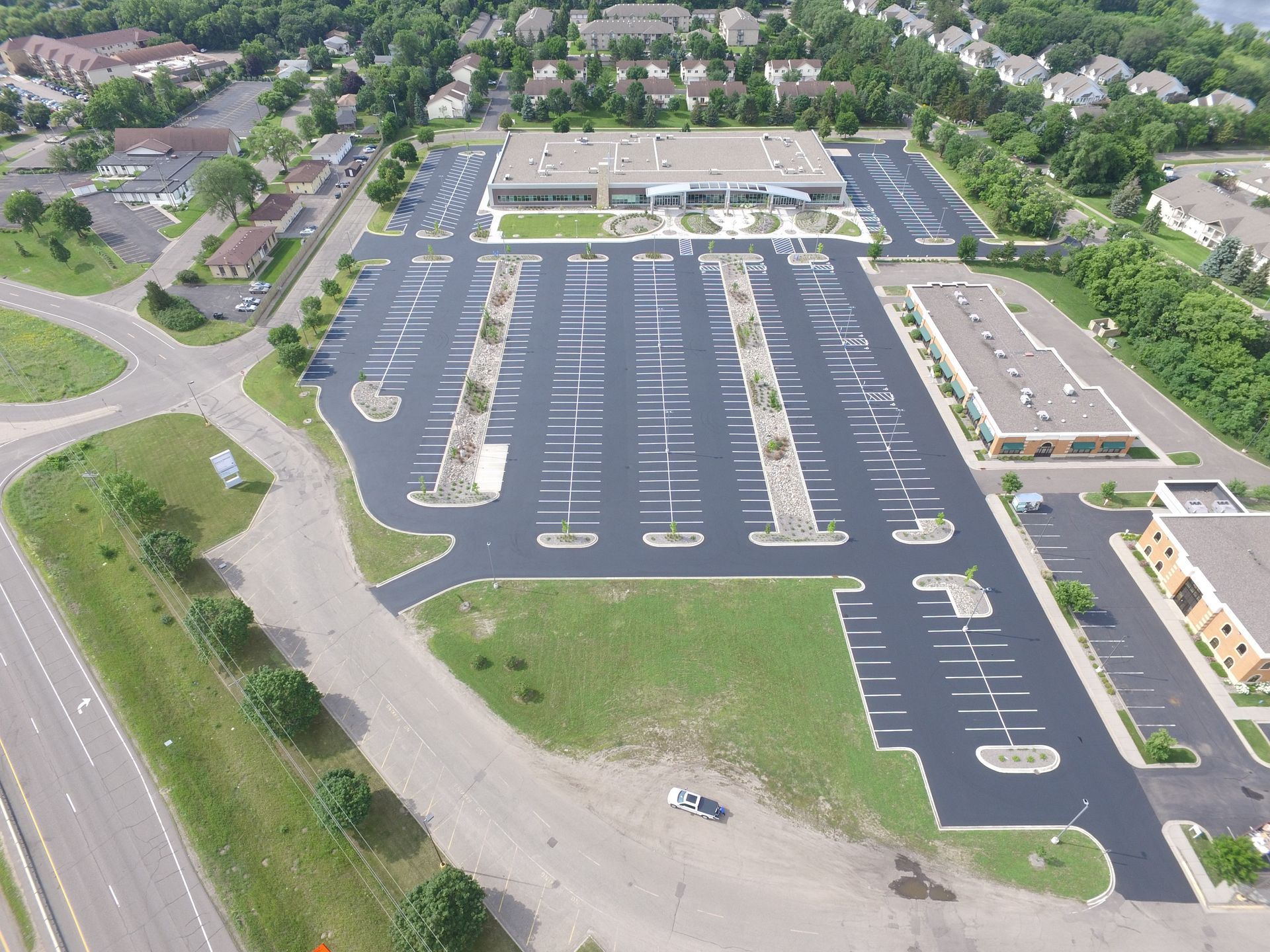 Aerial view of a large parking lot beside a shopping center and nearby neighborhood.
