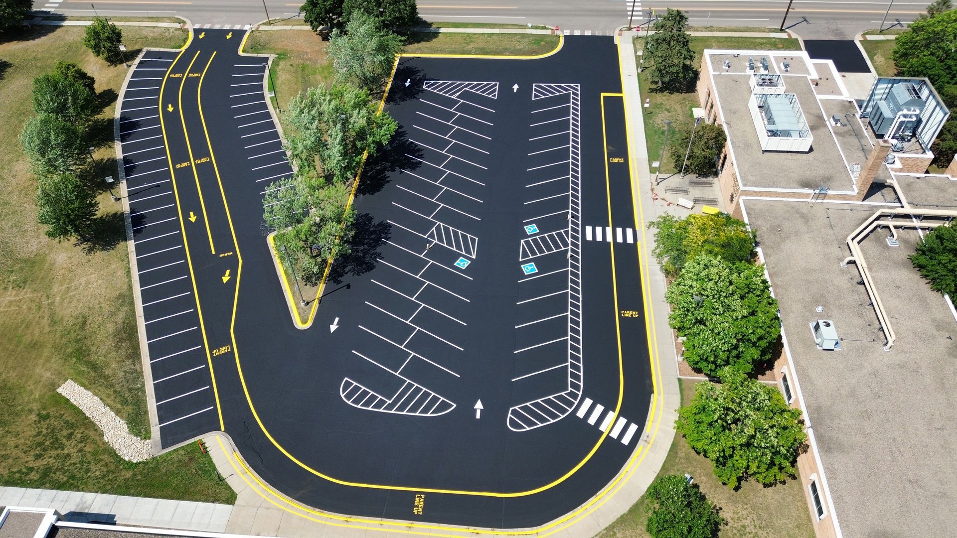 Aerial view of a mostly empty parking lot with painted spaces and a curved drive lane.