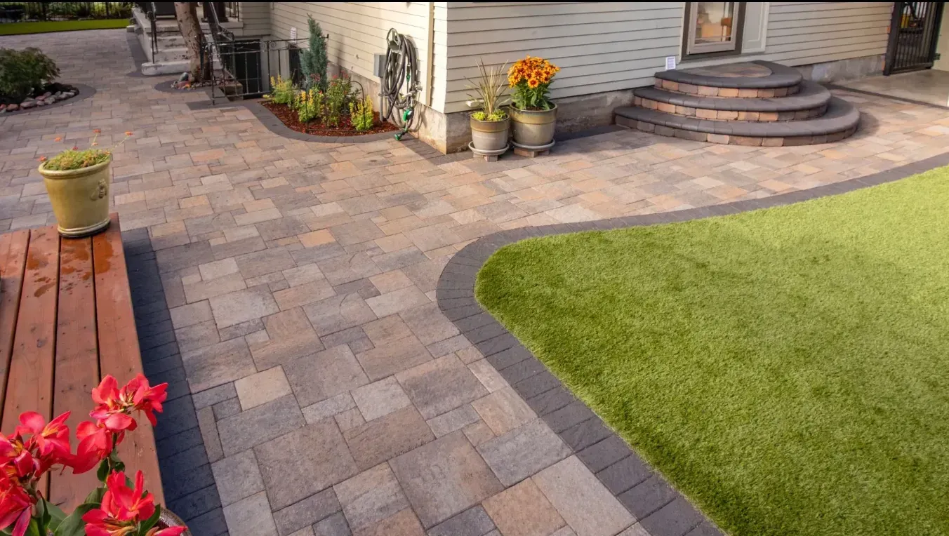 Brick pathway curves alongside green lawn, leading to a house.