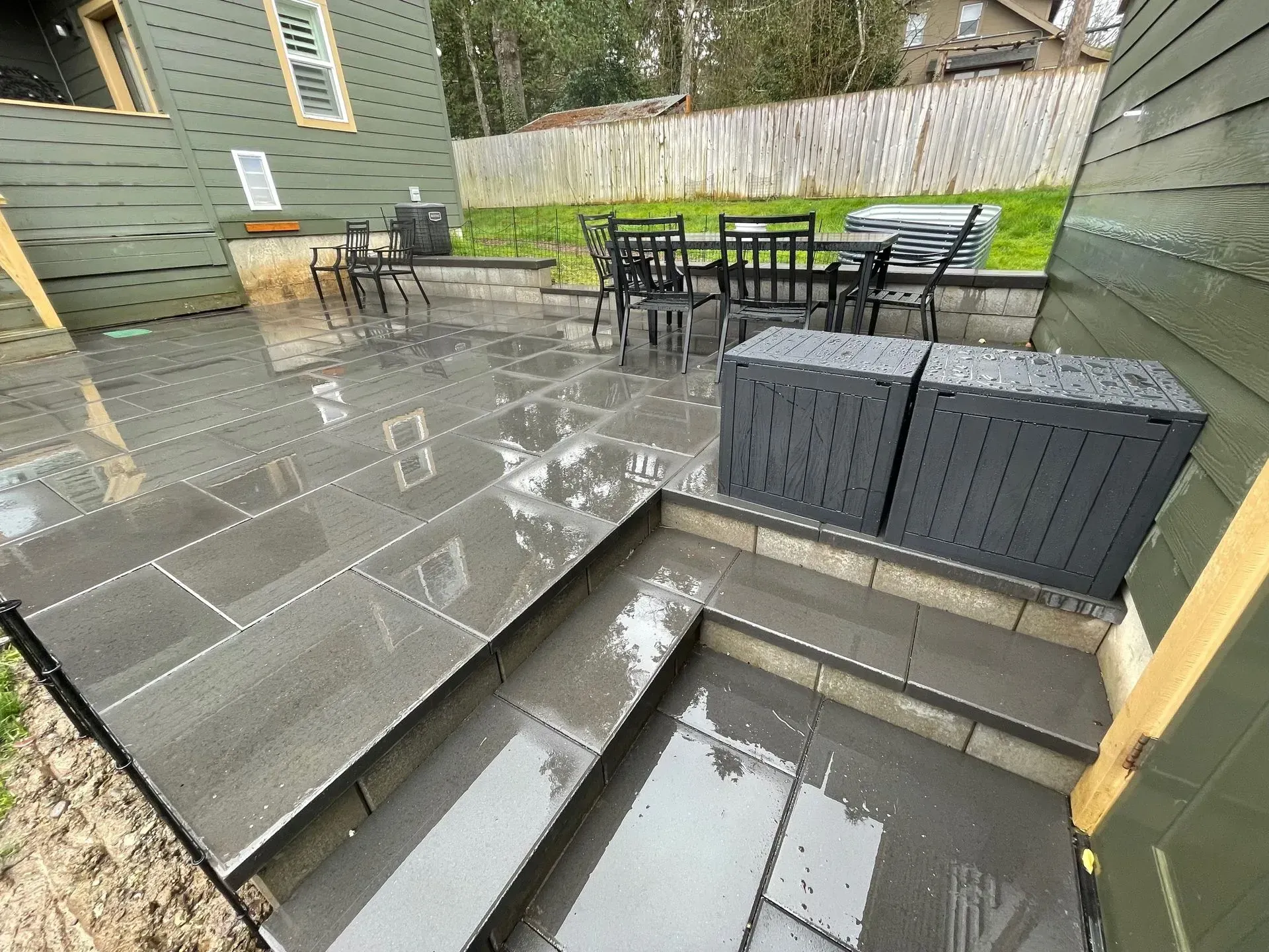 Newly constructed patio with gray pavers and steps. Outdoor dining set in the background.